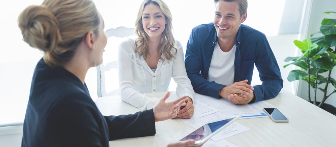 Insurance agent with couple looking through documents.